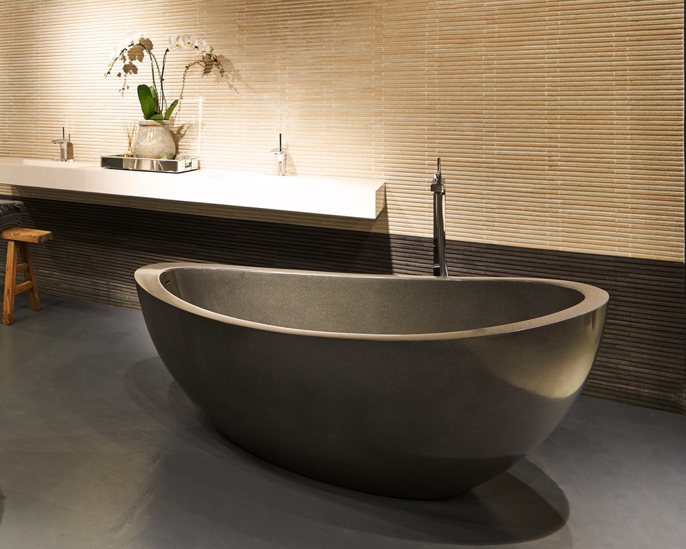 This is an example of a large contemporary master bathroom in Melbourne with an integrated sink, granite benchtops, a freestanding tub, gray tile, stone tile and concrete floors.