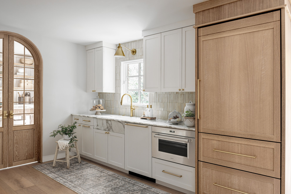Photo of a mid-sized transitional galley eat-in kitchen in DC Metro with an undermount sink, flat-panel cabinets, light wood cabinets, marble benchtops, beige splashback, brick splashback, panelled appliances, light hardwood floors, no island, beige floor and multi-coloured benchtop.
