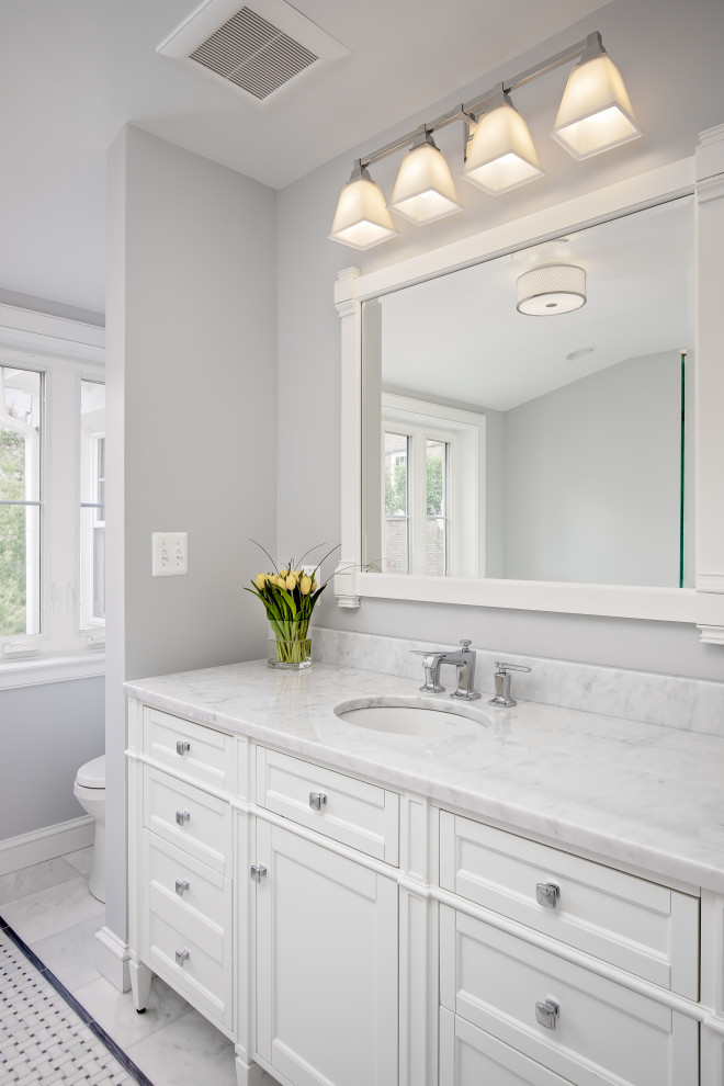 This is an example of a large traditional master bathroom in DC Metro with a single vanity, marble benchtops, a freestanding vanity, recessed-panel cabinets, white cabinets, a drop-in tub, a corner shower, a two-piece toilet, gray tile, marble, grey walls, marble floors, an undermount sink, grey floor, a hinged shower door, white benchtops and a niche.