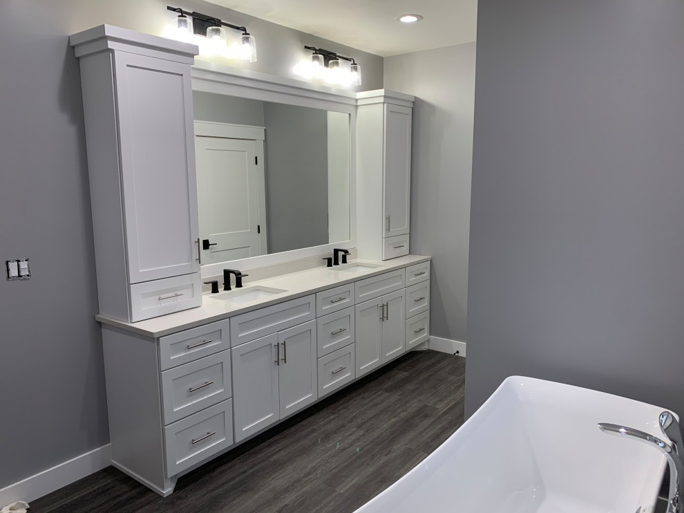 Photo of a mid-sized arts and crafts master bathroom in Huntington with shaker cabinets, white cabinets, a freestanding tub, grey walls, vinyl floors, an undermount sink, engineered quartz benchtops, grey floor, white benchtops, a double vanity and a built-in vanity.