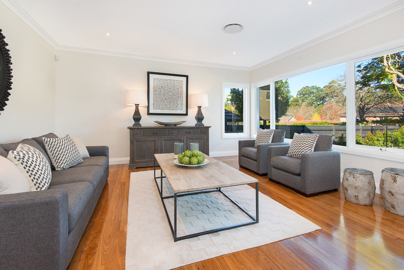 This is an example of a large midcentury formal enclosed living room in Sydney with beige walls and medium hardwood floors.