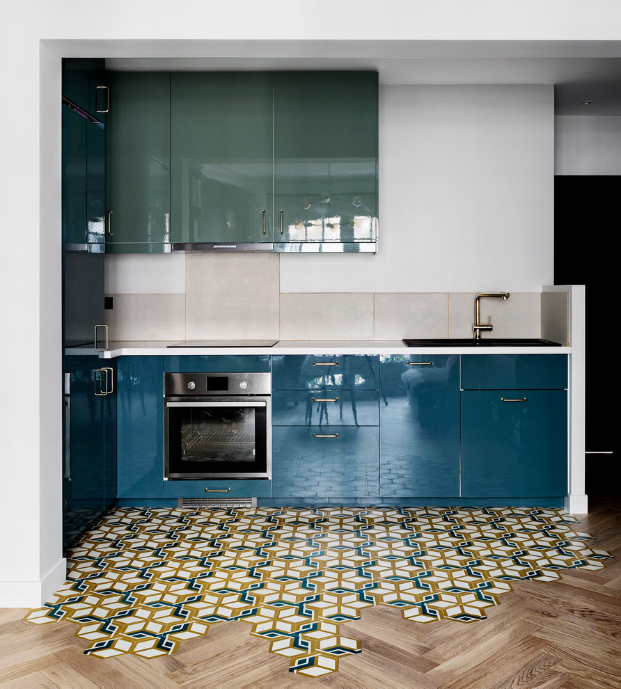 Mid-sized contemporary l-shaped open plan kitchen in Other with beige splashback, terra-cotta splashback, a single-bowl sink, beaded inset cabinets, blue cabinets, stainless steel appliances, cement tiles and white benchtop.
