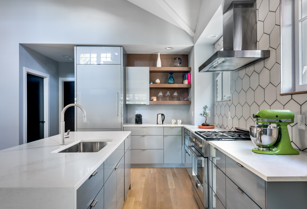 This is an example of a large contemporary l-shaped eat-in kitchen in Denver with an undermount sink, flat-panel cabinets, white splashback, porcelain splashback, stainless steel appliances, light hardwood floors, with island, beige floor, white benchtop and grey cabinets.