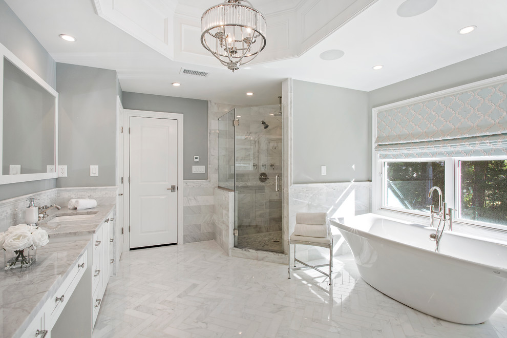 Design ideas for a large traditional ensuite bathroom in New York with white cabinets, a freestanding bath, grey walls, marble flooring, marble worktops, recessed-panel cabinets, a corner shower, marble tiles, a submerged sink and a hinged door.