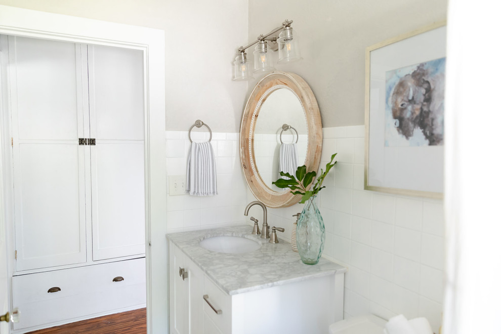 Cette photo montre une petite salle de bain craftsman avec un placard à porte shaker, des portes de placard blanches, une baignoire posée, WC séparés, un carrelage beige, des carreaux de céramique, un mur beige, un sol en carrelage de céramique, un lavabo encastré, un plan de toilette en marbre, un sol blanc, un plan de toilette gris, meuble simple vasque et meuble-lavabo sur pied.