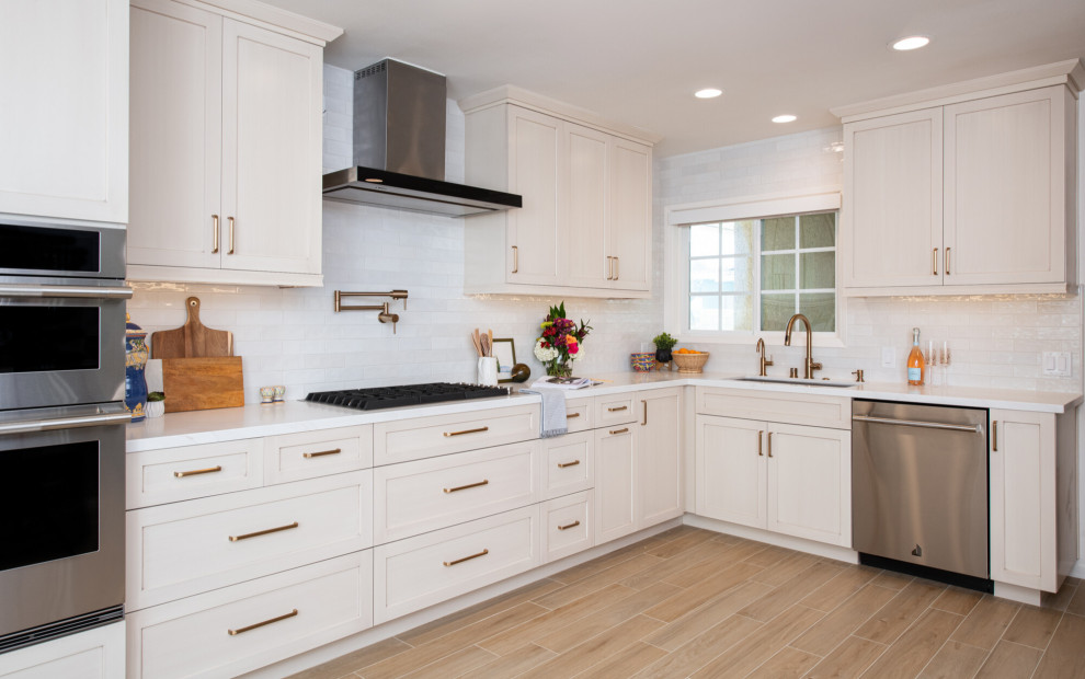 Klassisk inredning av ett vit vitt kök och matrum, med en undermonterad diskho, skåp i shakerstil, vita skåp, bänkskiva i kvarts, vitt stänkskydd, stänkskydd i keramik, rostfria vitvaror, klinkergolv i porslin och brunt golv