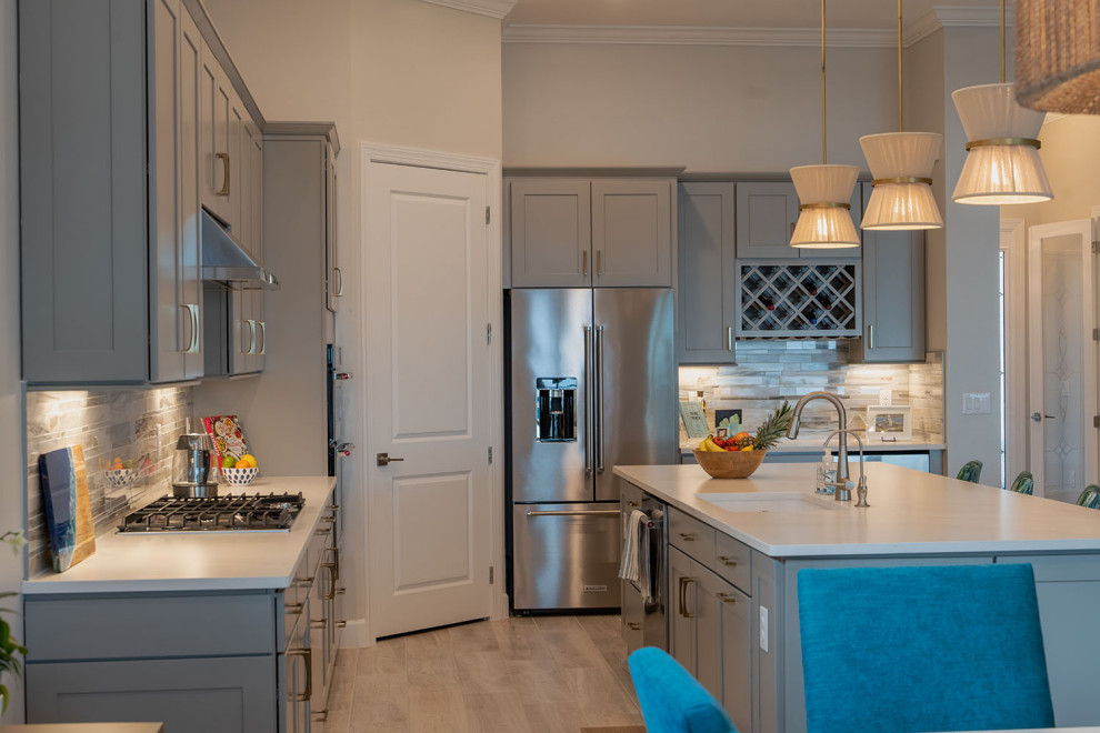 Medium sized modern galley open plan kitchen in Cedar Rapids with a submerged sink, shaker cabinets, grey cabinets, engineered stone countertops, multi-coloured splashback, stainless steel appliances, medium hardwood flooring, an island and white worktops.