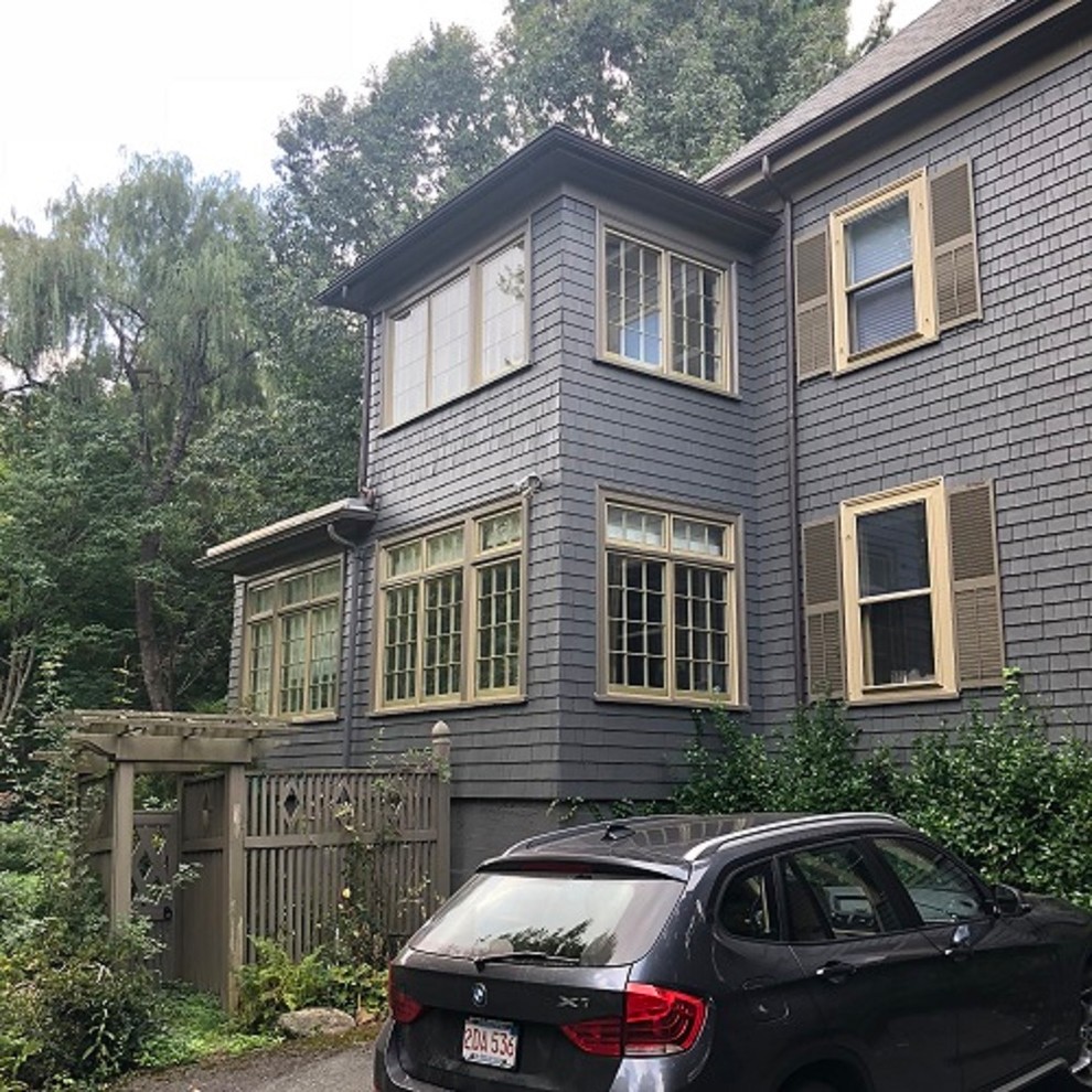This is an example of a large midcentury three-storey black house exterior in Boston with wood siding, a gable roof and a shingle roof.