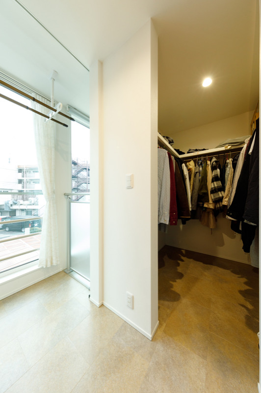 Small modern gender-neutral walk-in wardrobe in Tokyo Suburbs with open cabinets, white cabinets, porcelain floors, beige floor and wallpaper.
