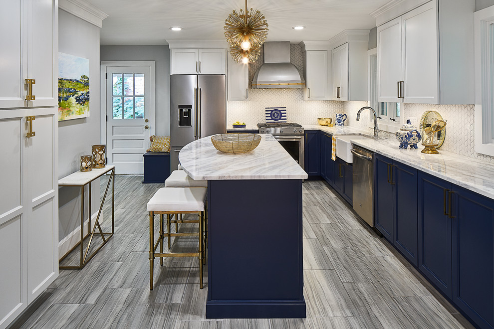 This is an example of a mid-sized transitional l-shaped eat-in kitchen in Charlotte with a farmhouse sink, recessed-panel cabinets, blue cabinets, marble benchtops, white splashback, mosaic tile splashback, stainless steel appliances, porcelain floors, with island, grey floor and white benchtop.