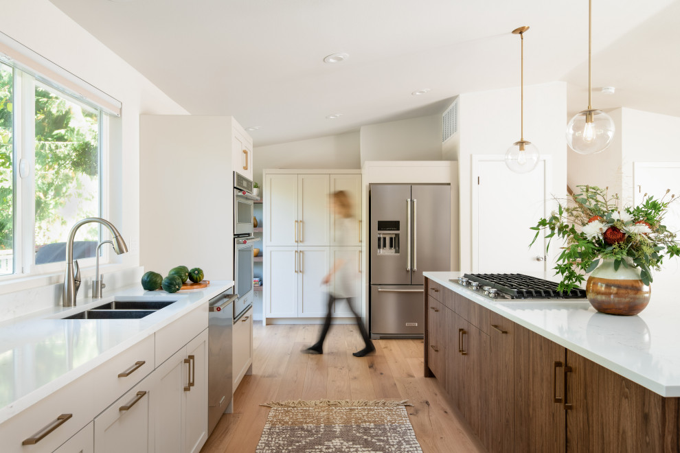 Inspiration for a large contemporary single-wall open plan kitchen in Seattle with a double-bowl sink, shaker cabinets, grey cabinets, quartz benchtops, white splashback, stainless steel appliances, light hardwood floors, with island, yellow floor and white benchtop.