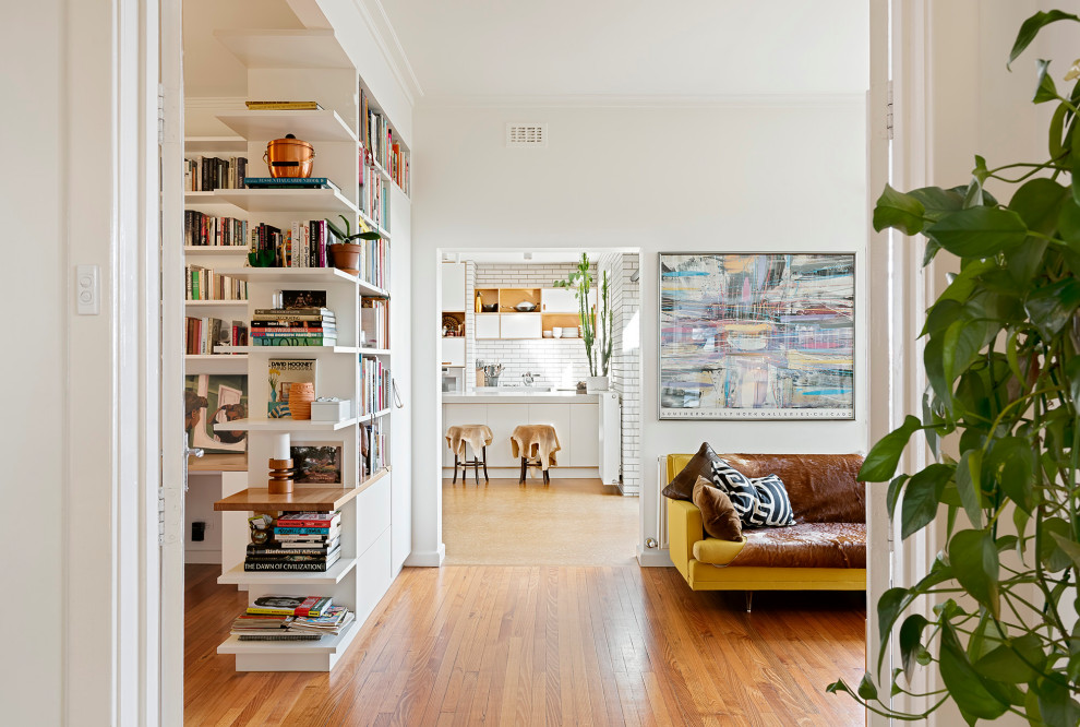 Design ideas for a contemporary open concept living room in Melbourne with a library, white walls and light hardwood floors.