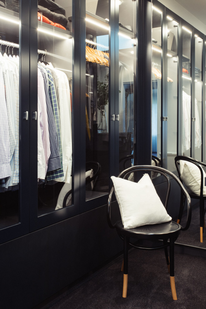 Ejemplo de armario vestidor unisex minimalista extra grande con armarios tipo vitrina, puertas de armario negras, moqueta y suelo negro