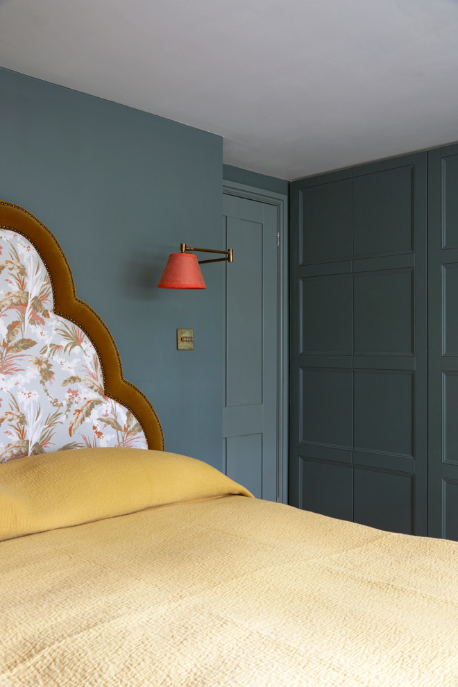 Medium sized traditional master bedroom in London with green walls, medium hardwood flooring, beige floors and panelled walls.
