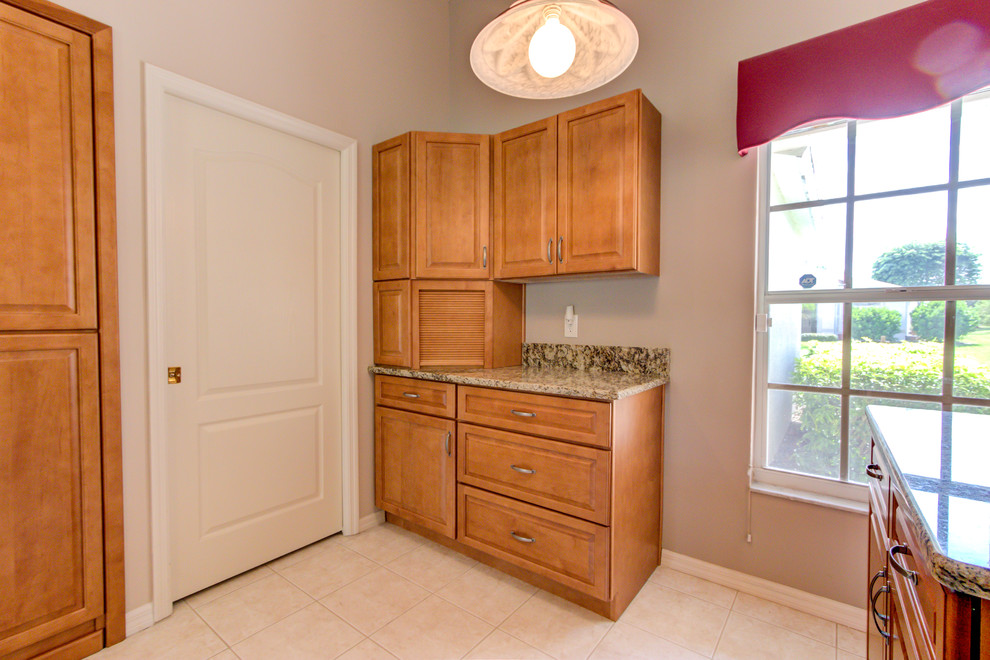 Example of a mid-sized kitchen design with an undermount sink, raised-panel cabinets, medium tone wood cabinets, granite countertops, white appliances and brown countertops