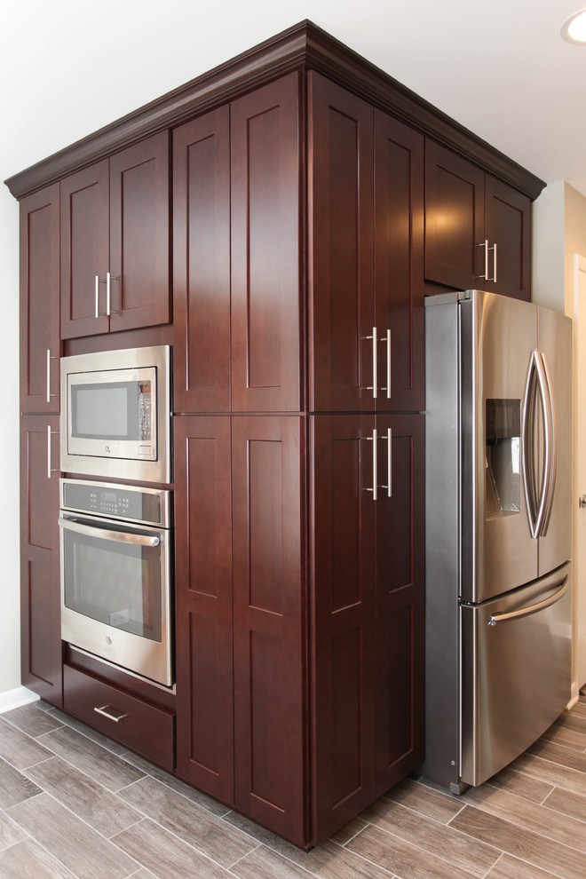Inspiration for a large transitional u-shaped porcelain tile eat-in kitchen remodel in Chicago with an undermount sink, recessed-panel cabinets, dark wood cabinets, granite countertops, gray backsplash, glass tile backsplash, stainless steel appliances and an island