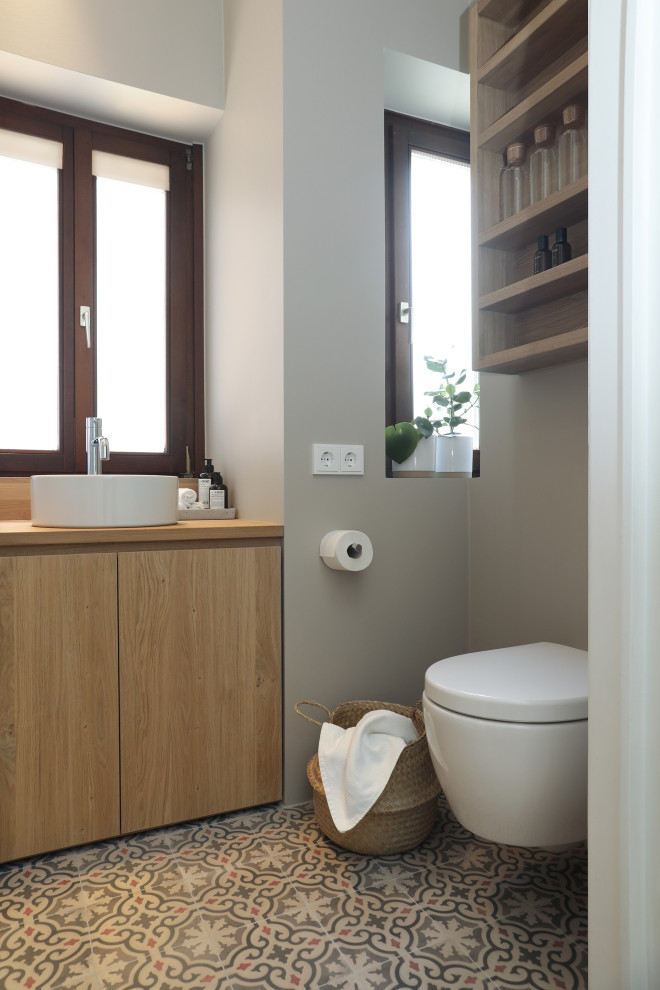 This is an example of a small modern 3/4 bathroom in Frankfurt with flat-panel cabinets, light wood cabinets, an alcove shower, a two-piece toilet, gray tile, grey walls, cement tiles, a vessel sink, wood benchtops, multi-coloured floor, an open shower, a single vanity, a built-in vanity, wallpaper and wallpaper.