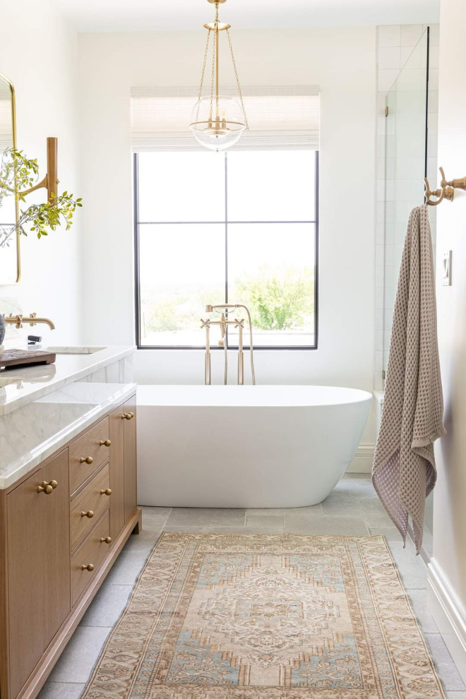 Foto på ett stort lantligt vit en-suite badrum, med släta luckor, skåp i ljust trä, ett fristående badkar, klinkergolv i porslin, marmorbänkskiva och vitt golv
