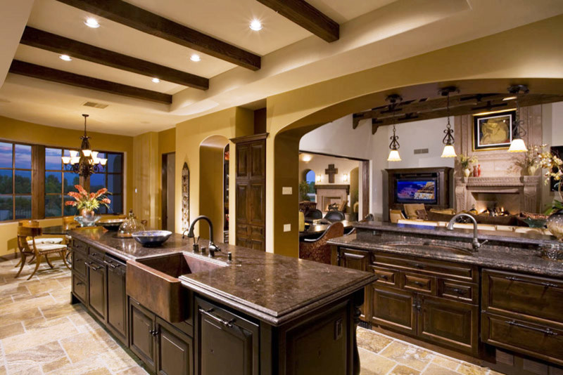 Design ideas for a large mediterranean u-shaped open plan kitchen in Orange County with a farmhouse sink, raised-panel cabinets, dark wood cabinets, quartzite benchtops, panelled appliances, terra-cotta floors and with island.