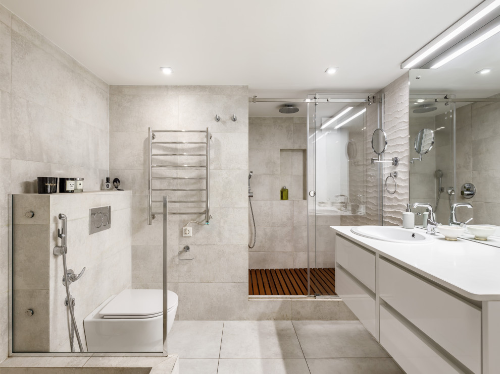 Minimalistisk inredning av ett mellanstort vit vitt badrum med dusch, med släta luckor, vita skåp, en vägghängd toalettstol, beige kakel, porslinskakel, beige väggar, klinkergolv i porslin, ett nedsänkt handfat, bänkskiva i kvarts, beiget golv och dusch med skjutdörr