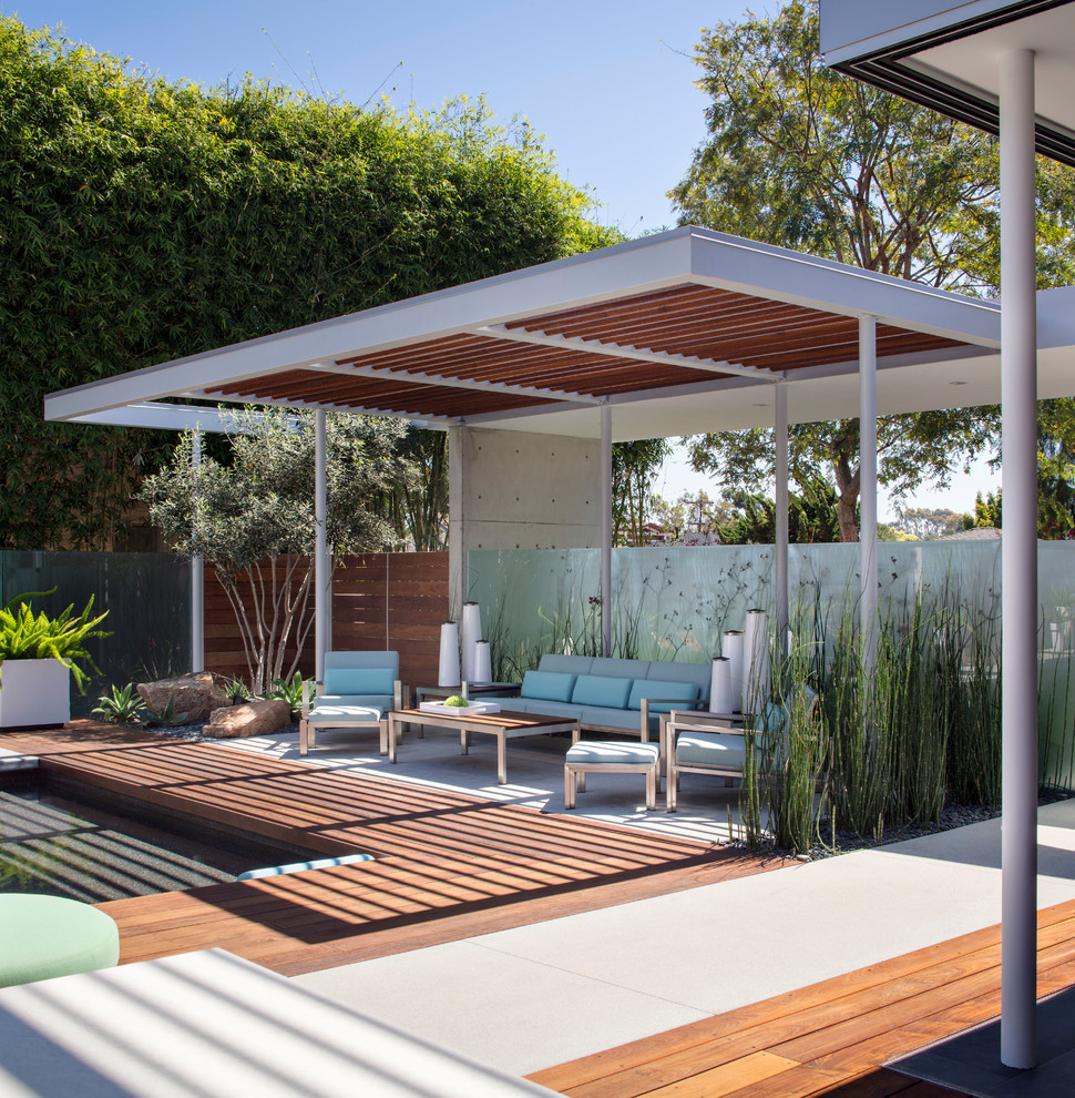 Large modern backyard rectangular pool in San Diego with a pool house and concrete slab.