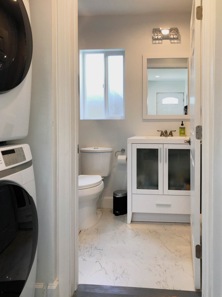 Photo of a mid-sized transitional 3/4 bathroom in Los Angeles with glass-front cabinets, white cabinets, an alcove shower, a two-piece toilet, brown tile, white floor, a sliding shower screen, white benchtops, a corner tub, ceramic tile, beige walls, a drop-in sink, a laundry, a single vanity, a freestanding vanity and ceramic floors.