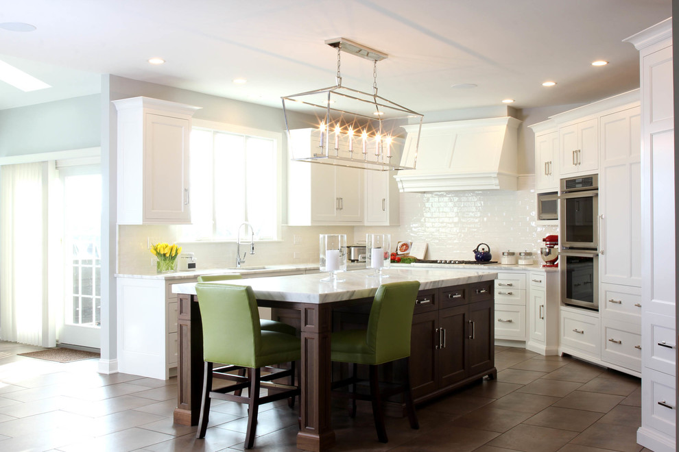 This is an example of a mid-sized transitional u-shaped eat-in kitchen in Philadelphia with an undermount sink, beaded inset cabinets, white cabinets, marble benchtops, white splashback, ceramic splashback, stainless steel appliances and porcelain floors.