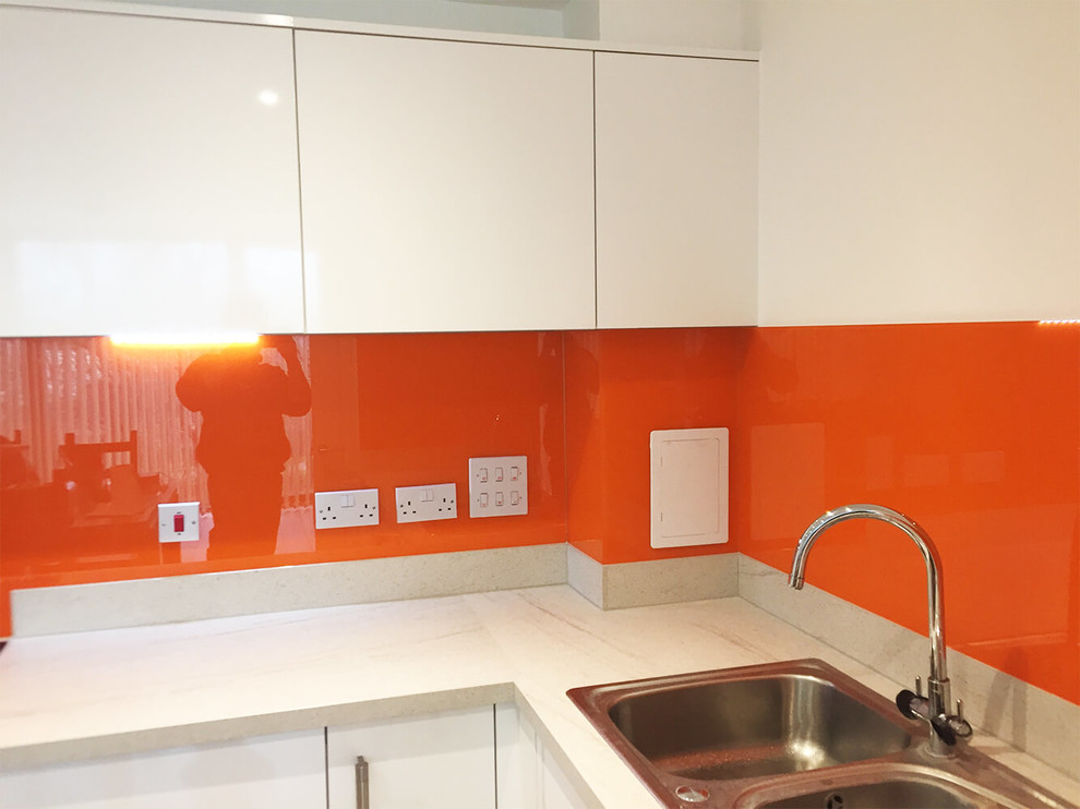 Design ideas for a large modern eat-in kitchen in Hertfordshire with flat-panel cabinets, white cabinets, marble benchtops, orange splashback, glass sheet splashback and no island.