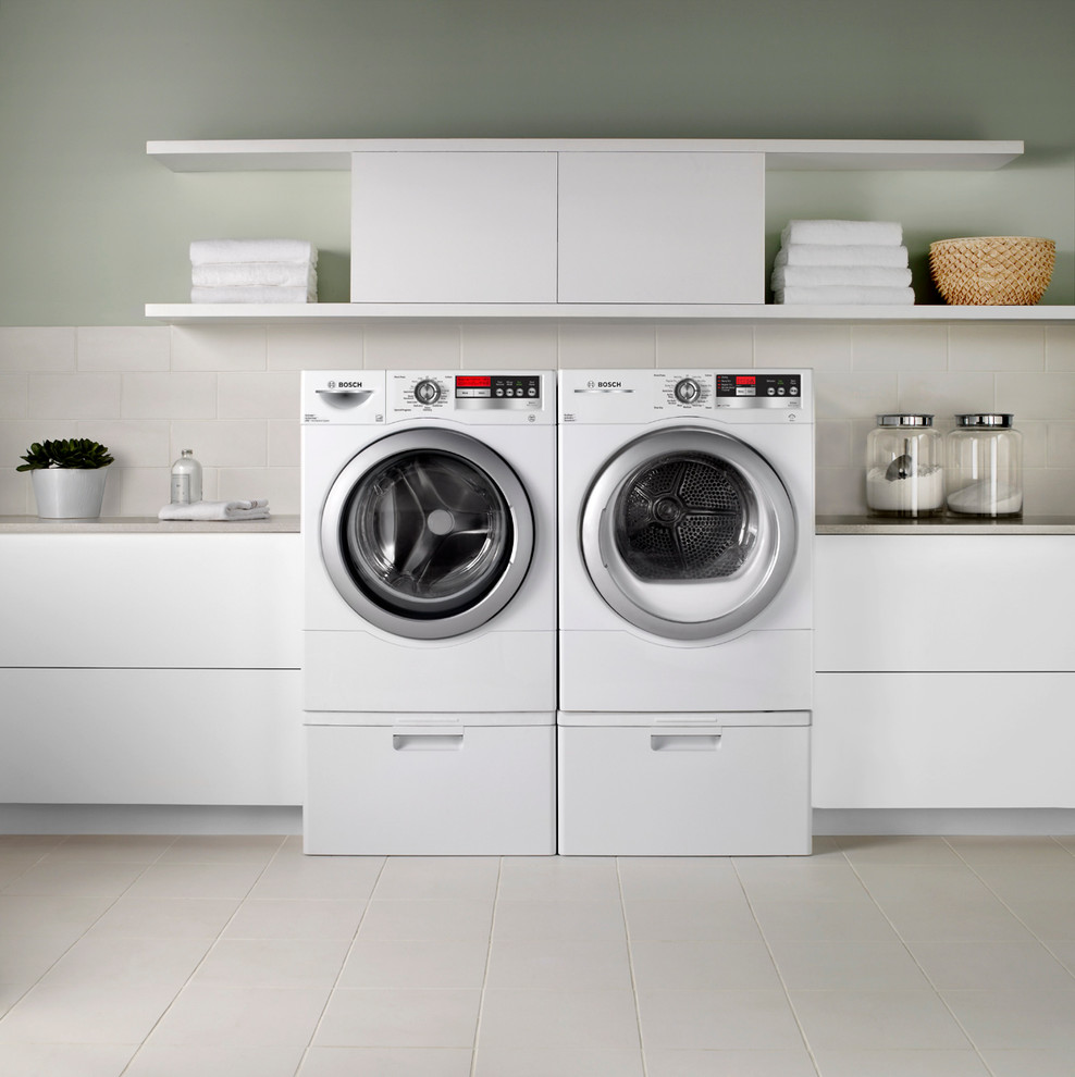 Inspiration for a mid-sized modern single-wall dedicated laundry room in Boston with flat-panel cabinets, white cabinets, solid surface benchtops, grey walls, ceramic floors, a side-by-side washer and dryer and beige floor.