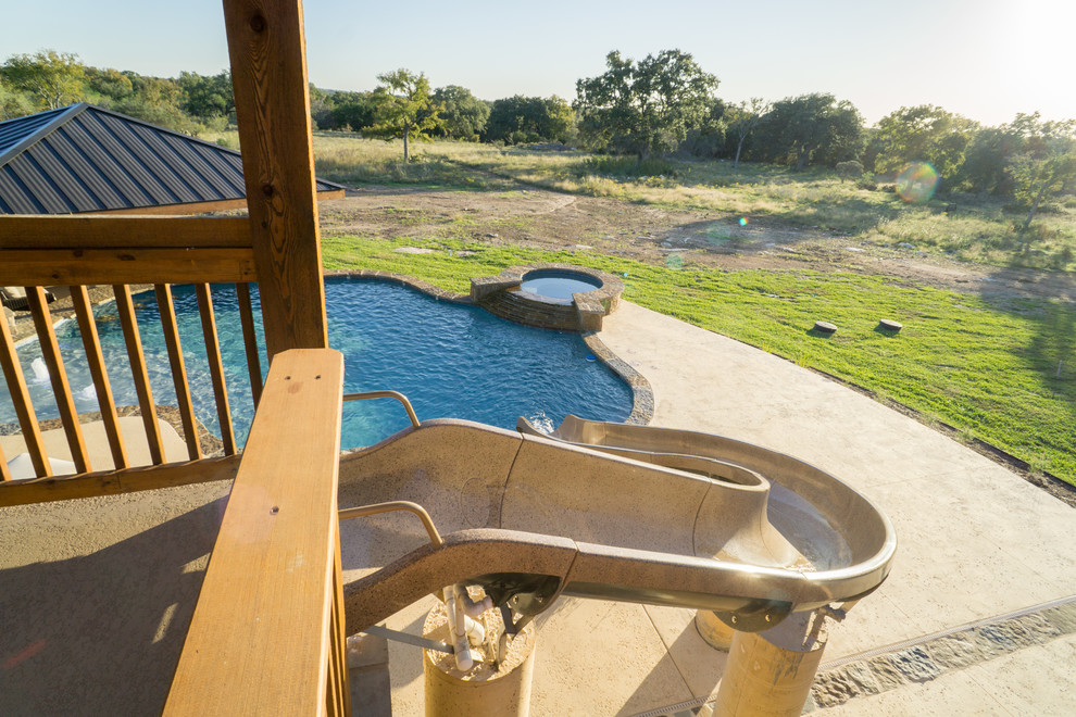 Large mountain style backyard stone and custom-shaped pool fountain photo in Austin