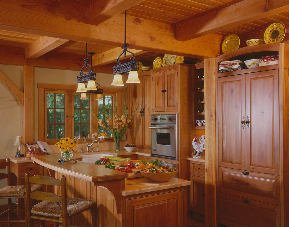 Traditional l-shaped eat-in kitchen in Boston with a drop-in sink, raised-panel cabinets, medium wood cabinets, stainless steel appliances and with island.