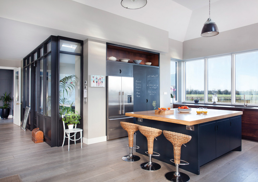 Photo of a large contemporary u-shaped kitchen in Other with flat-panel cabinets, dark wood cabinets, wood benchtops, grey splashback, stainless steel appliances and with island.