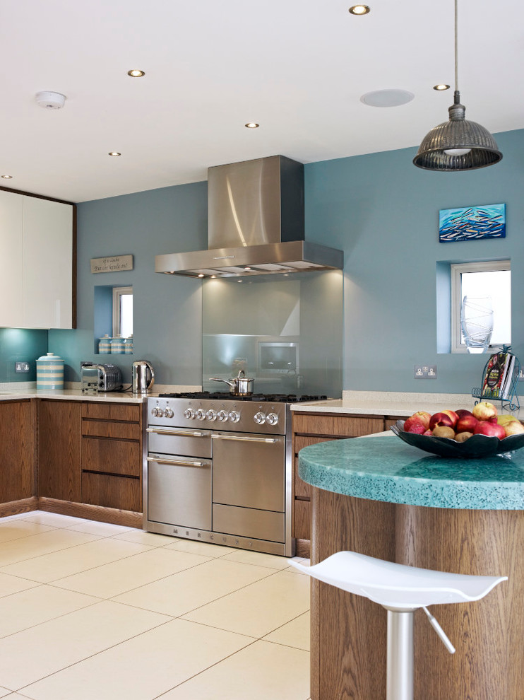This is an example of a mid-sized contemporary eat-in kitchen in London with flat-panel cabinets, medium wood cabinets, recycled glass benchtops, stainless steel appliances and a peninsula.