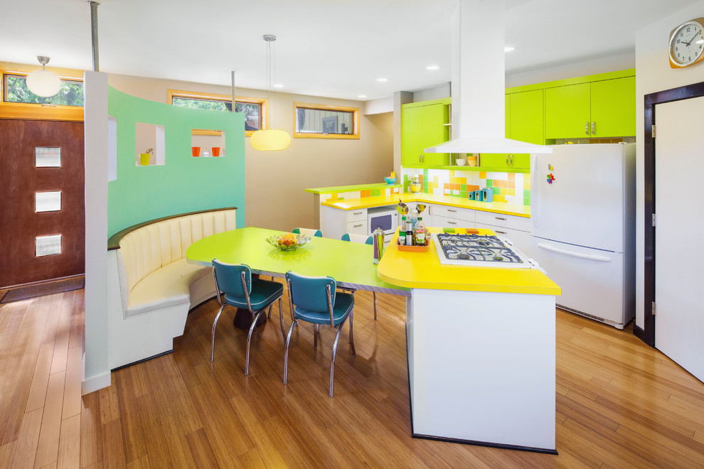 This is an example of a midcentury l-shaped kitchen in Austin with flat-panel cabinets, green cabinets, multi-coloured splashback, white appliances, medium hardwood floors and yellow benchtop.