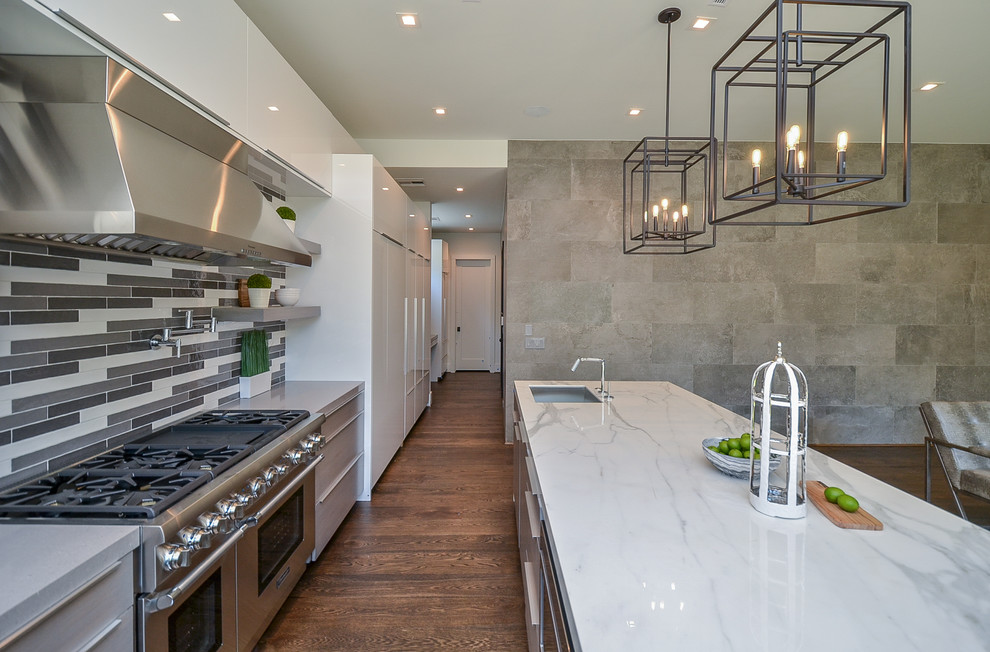 Open concept kitchen - mid-sized transitional l-shaped medium tone wood floor open concept kitchen idea in Houston with a single-bowl sink, flat-panel cabinets, white cabinets, marble countertops, multicolored backsplash, glass tile backsplash, stainless steel appliances, an island and white countertops