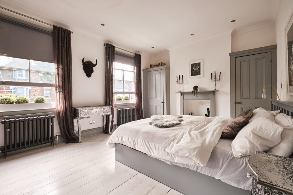 Imagen de dormitorio principal y gris y blanco nórdico de tamaño medio con paredes blancas, suelo de madera pintada, todas las chimeneas, marco de chimenea de madera y suelo blanco