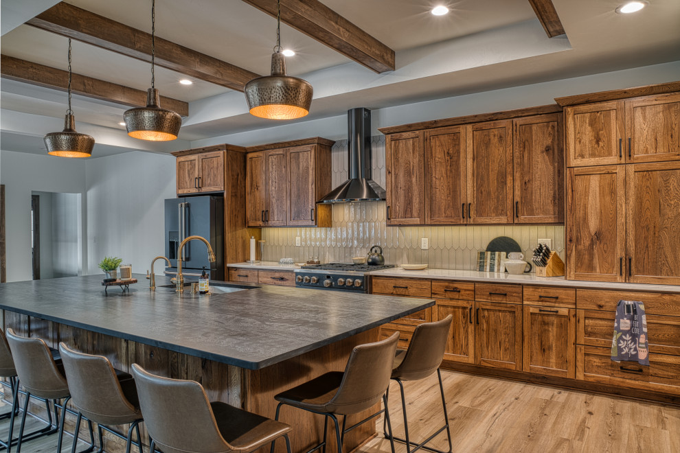 Example of a large transitional l-shaped vinyl floor, beige floor and tray ceiling open concept kitchen design with an undermount sink, shaker cabinets, medium tone wood cabinets, quartz countertops, beige backsplash, ceramic backsplash, stainless steel appliances, an island and multicolored countertops