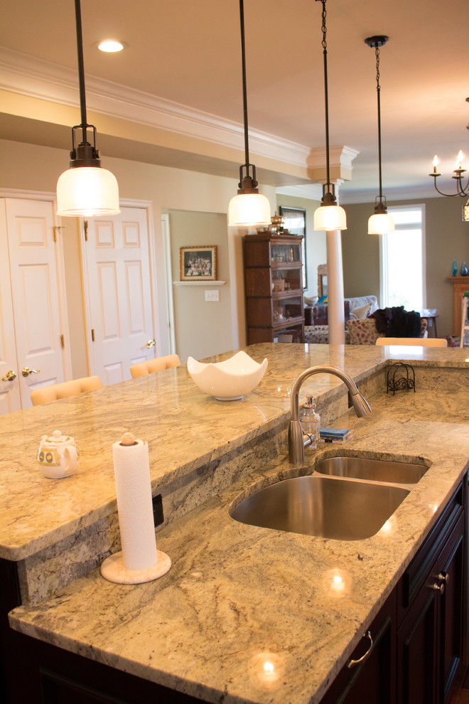 Enclosed kitchen - large transitional l-shaped dark wood floor and brown floor enclosed kitchen idea in DC Metro with a double-bowl sink, raised-panel cabinets, dark wood cabinets, granite countertops, beige backsplash, limestone backsplash, stainless steel appliances and an island