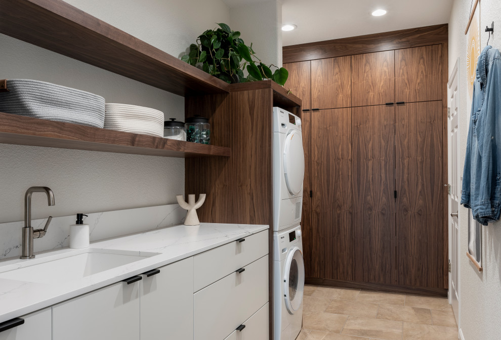 Medium sized contemporary l-shaped separated utility room in Sacramento with a submerged sink, flat-panel cabinets, dark wood cabinets, engineered stone countertops, white walls, ceramic flooring, a stacked washer and dryer, beige floors and white worktops.
