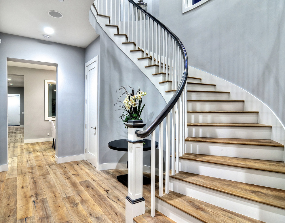 Example of a large transitional wooden curved staircase design in Orange County with wooden risers