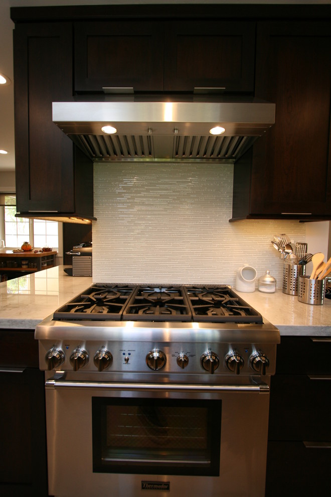 Mid-sized transitional l-shaped porcelain tile kitchen photo in Orange County with a double-bowl sink, recessed-panel cabinets, dark wood cabinets, quartzite countertops, white backsplash, glass tile backsplash, stainless steel appliances and no island