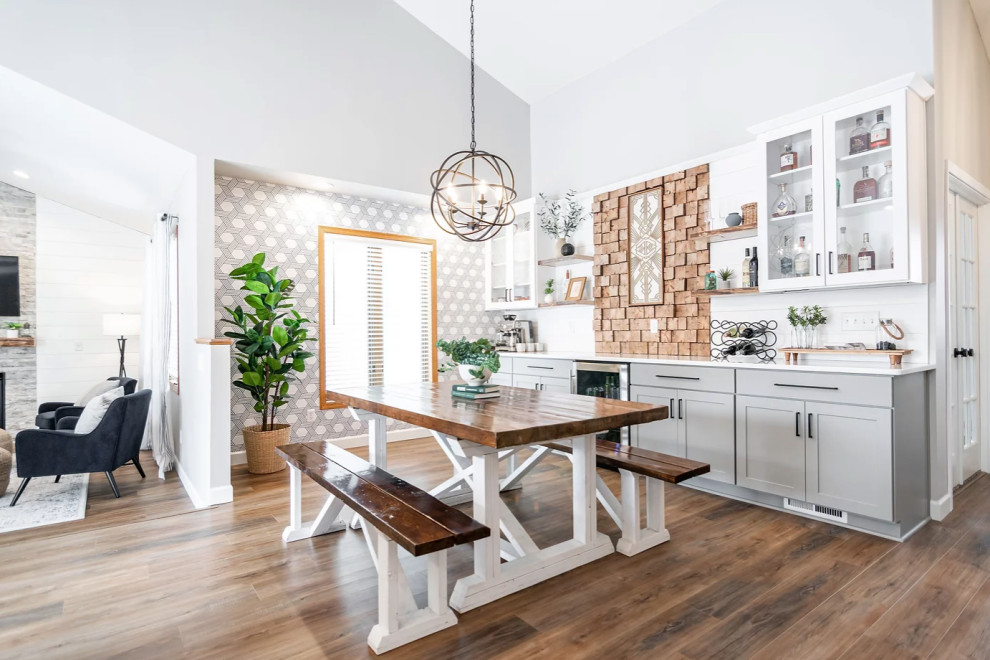 Immagine di una grande sala da pranzo aperta verso la cucina scandinava con pareti grigie, pavimento in legno massello medio, pavimento marrone e pareti in perlinato