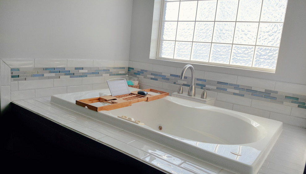 Bild på ett mellanstort funkis beige beige en-suite badrum, med blå skåp, ett platsbyggt badkar, blå kakel, glaskakel, vita väggar, bänkskiva i onyx och brunt golv