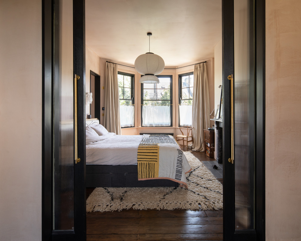 Design ideas for an eclectic bedroom in London with pink walls, dark hardwood floors and brown floor.