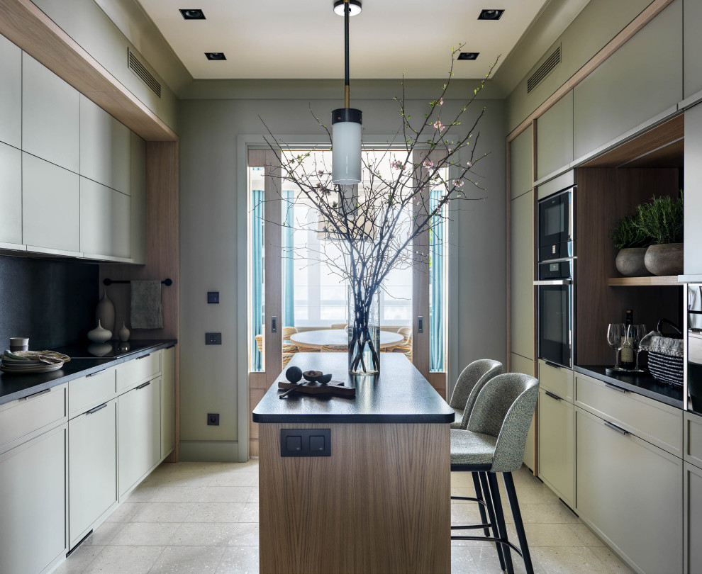 Photo of a mid-sized contemporary galley separate kitchen in Moscow with recessed-panel cabinets, green cabinets, granite benchtops, black splashback, stone slab splashback, black appliances, terrazzo floors, with island, white floor and black benchtop.
