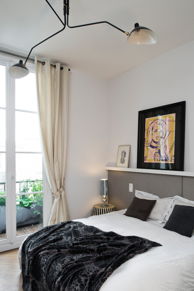 Inspiration for a contemporary bedroom in Paris with white walls, medium hardwood floors and brown floor.