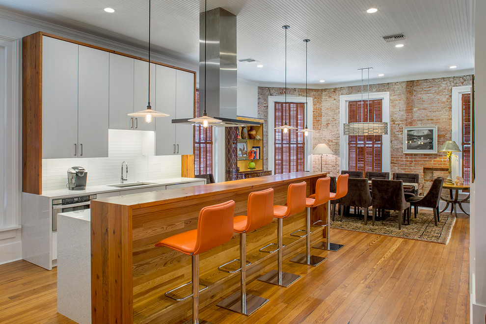 Large industrial eat-in kitchen in Houston with an undermount sink, flat-panel cabinets, white cabinets, quartz benchtops, glass tile splashback, with island, white benchtop, white splashback and medium hardwood floors.