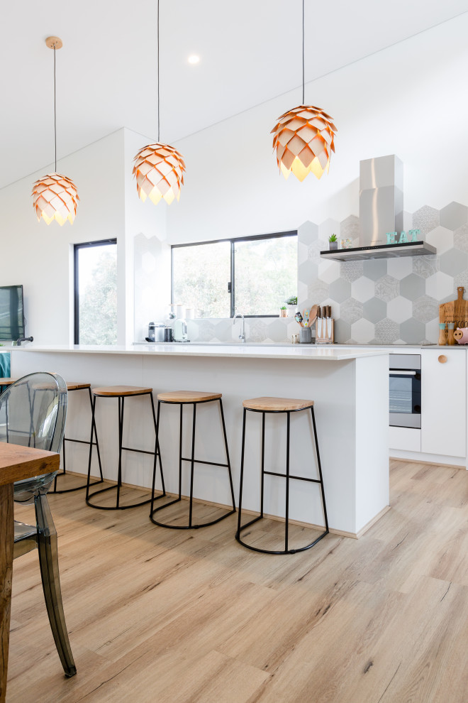 Design ideas for a large contemporary galley eat-in kitchen in Perth with flat-panel cabinets, white cabinets, green splashback, mosaic tile splashback, stainless steel appliances, light hardwood floors, with island, beige floor and white benchtop.