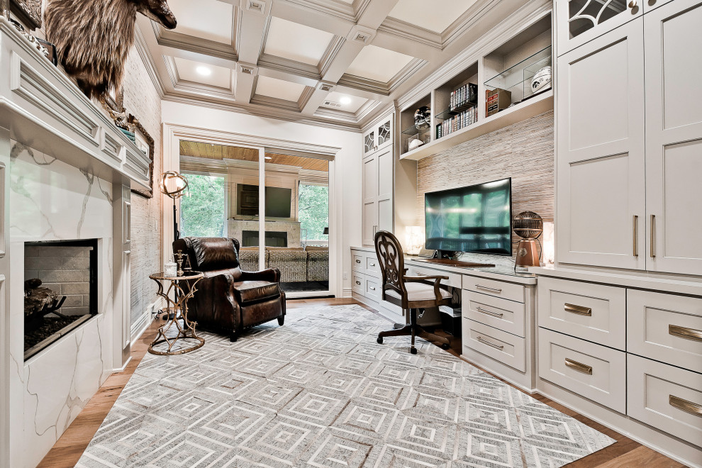 Inspiration for a mid-sized transitional study room in Other with grey walls, a two-sided fireplace, a stone fireplace surround, a built-in desk, coffered and light hardwood floors.