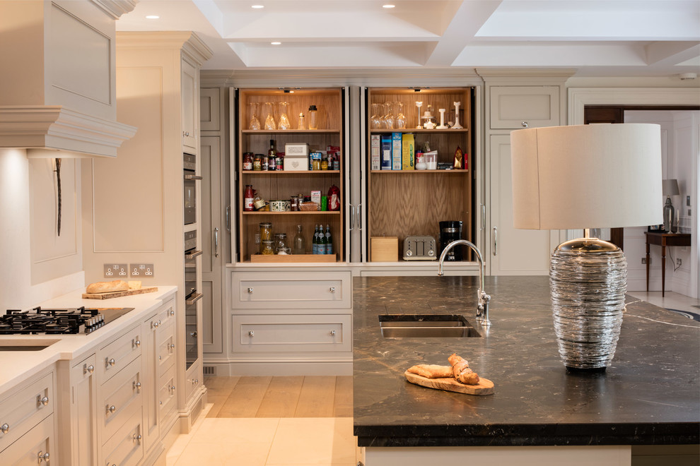 This is an example of a large traditional u-shaped eat-in kitchen in Dublin with an undermount sink, shaker cabinets, limestone benchtops, stone slab splashback, black appliances, medium hardwood floors and with island.